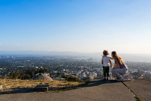 A young child and an adult looking out at the view of the city down below